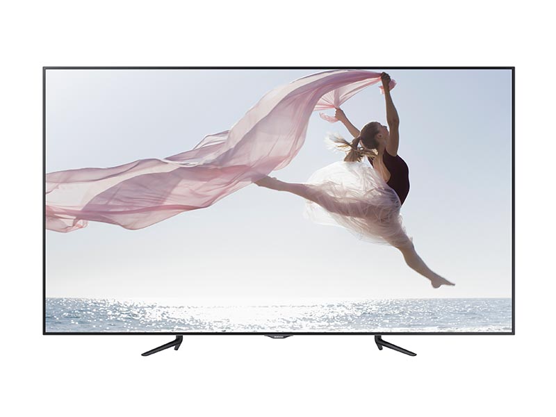 95 Inch LED LCD Samsung ME95C rental TV displaying a vivid image of a woman in a pink dress leaping by the ocean, holding flowing pink fabric under a bright sky. Large commercial digital display ideal for impactful visuals and presentations.