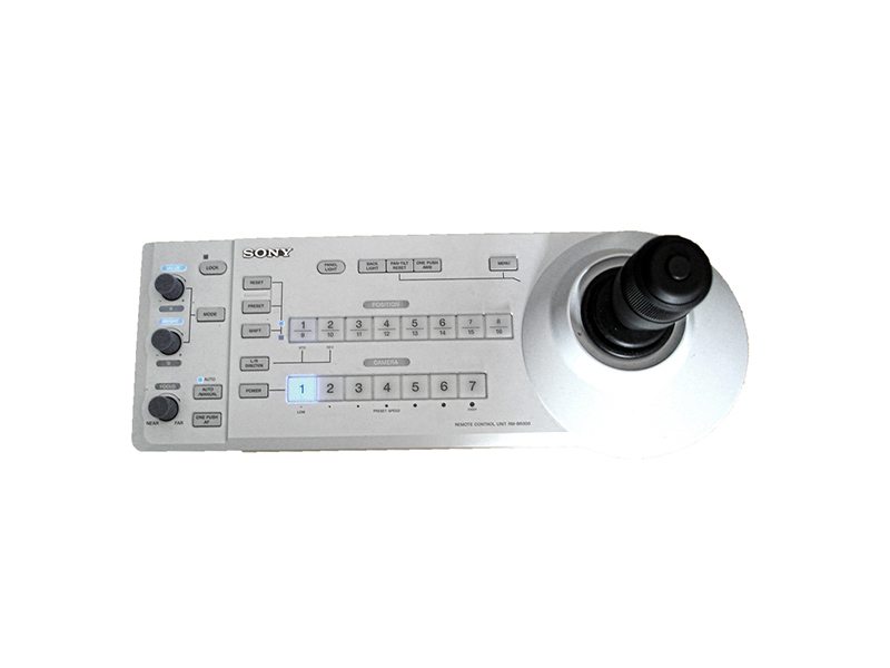 The PTZ camera remote control RM-BR300 is a white panel with numerous buttons, dials, and a large black joystick on the right, designed for precise camera or broadcast equipment operation—ideal for rental use.