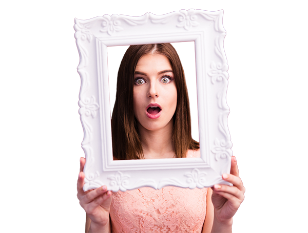 Surprised young woman with long brown hair wearing a pink lace top holds an ornate white picture frame in front of her face, wide-eyed and mouth open, against a burgundy background. Perfect for decorative photo frames or fashion tops.