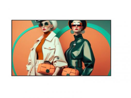 Two fashionable women pose in front of a geometric orange and teal background, each holding an orange handbag. One wears a beige coat, hat, and sunglasses; the other sports a dark green jacket with bold earrings. Stylish outfits highlight the latest womens fashion trends.