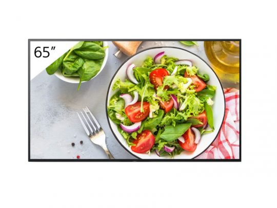 Samsung 65-Inch 4K UHD Smart TV displays a vibrant image of a fresh salad with lettuce, spinach, tomatoes, and red onions. Nearby on the light table are a fork, a bowl of spinach, olive oil bottle, and a red-checkered napkin, highlighting the TV’s lifelike color and clarity.