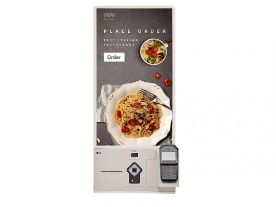 Selbstbedienungs-Bestellterminal mit Touchscreen, auf dem ein Menü mit Foto von Pasta und Salat sowie der Hinweis "Place Order" angezeigt wird; unterhalb des Bildschirms ist ein Kartenlesegerät für kontaktlose Bezahlung angebracht.